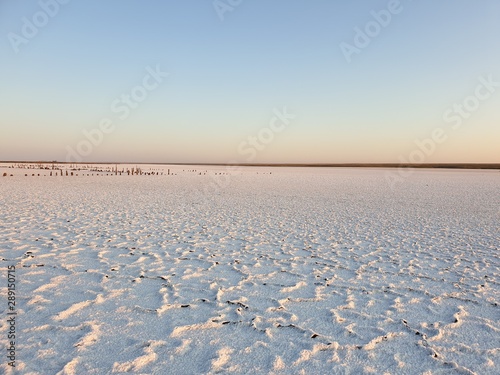 white surface of the lake covered with salt at sunrise