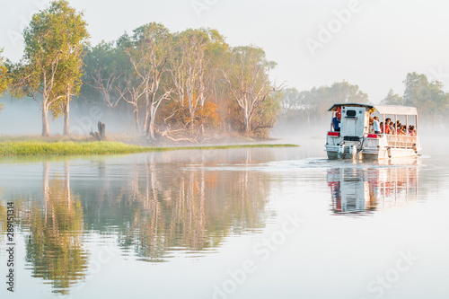 Obraz na płótnie A boat of the Yellow Water Cruise floats in the morning mist on the billabong at sunrise, Kakadu National Park, Northern Territory, Australia w salonie