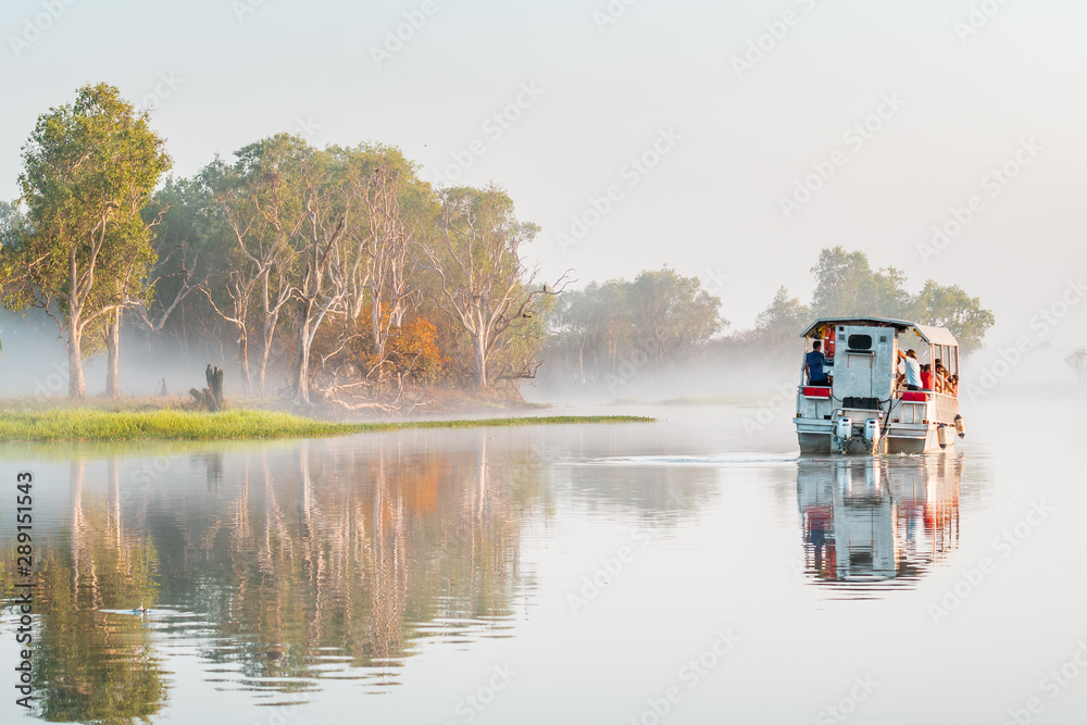 Φωτογραφία A boat of the Yellow Water Cruise floats in the morning mist on the billabong at