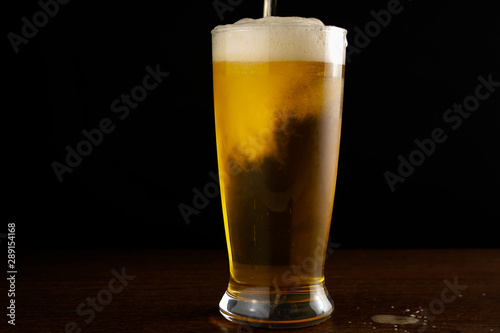 light beer is poured into a glass on a dark background