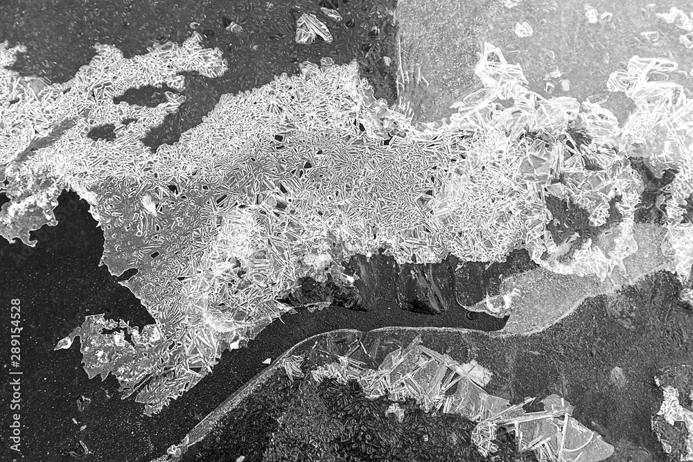 The texture of the ice crust on the pavement, black and white photo, background