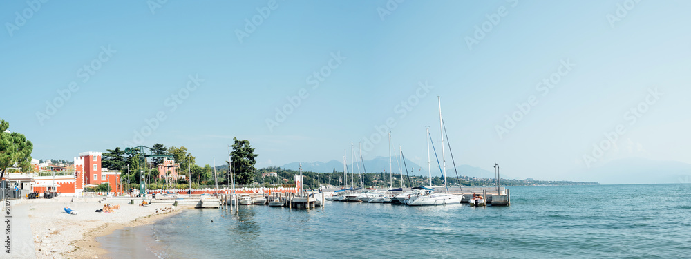 Padenghe del Garda, Italy - Sunday 1 September 2019: marina and bathers on the shores of Lake Garda on a sunny morning