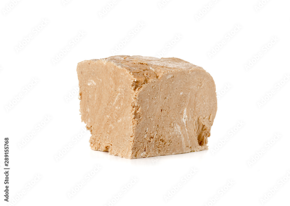 Halva on a white background. Arabian sweetness of caramel mass and ground roasted kernels of nuts, peanuts, close-up. Halva on a white background. Arabian sweetness of caramel mass and ground roasted kernels of nuts, peanuts, close-up.