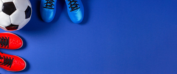 Soccer football background. Top view of soccer ball and two pair of soccer football sports shoes on blue background