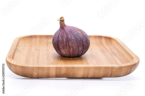 One whole fresh fig fruit on bamboo plate isolated on white background photo