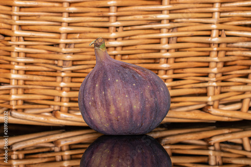 One whole fresh fig fruit with braided rattan behind photo