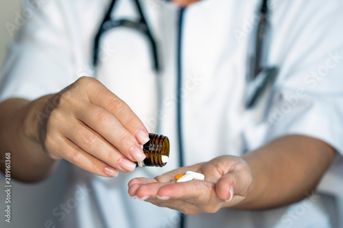 Female doctor hands holding bottle with pills, doctor giving pills, pharmacy concept