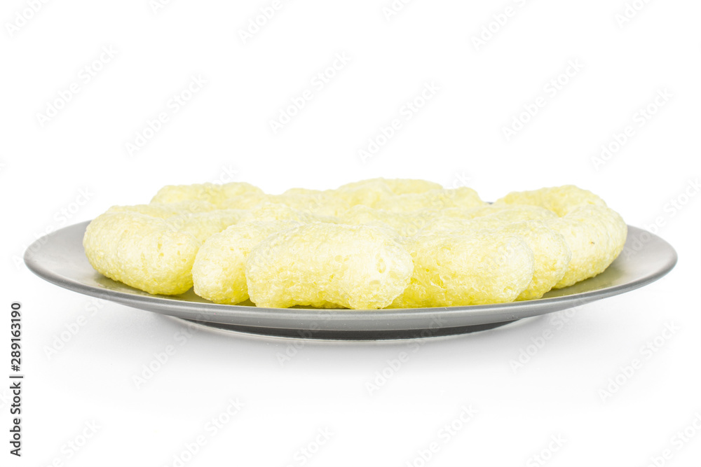 Lot of whole salted yellow corn puff on gray ceramic plate isolated on white background Lot of whole salted yellow corn puff on gray ceramic plate isolated on white background