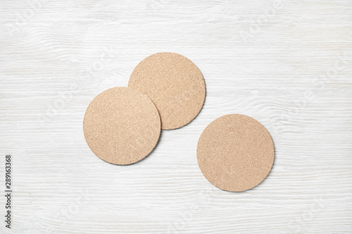 Blank cork beer coasters on light wooden background. Flat lay.