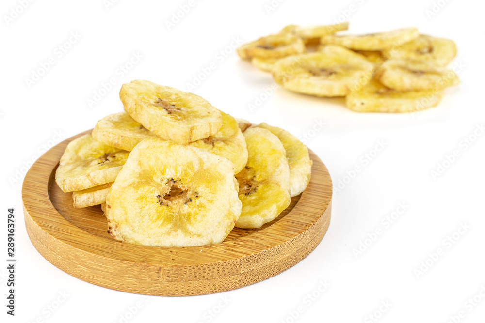 Lot of slices of sweet yellow dry banana on bamboo coaster isolated on white background Lot of slices of sweet yellow dry banana on bamboo coaster isolated on white background