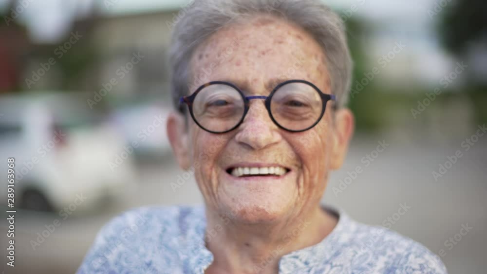 Portrait of happy elderly woman with black round glasses looking at camera and smiling with white teeth. Portrait of happy elderly woman with black round glasses looking at camera and smiling with white teeth.