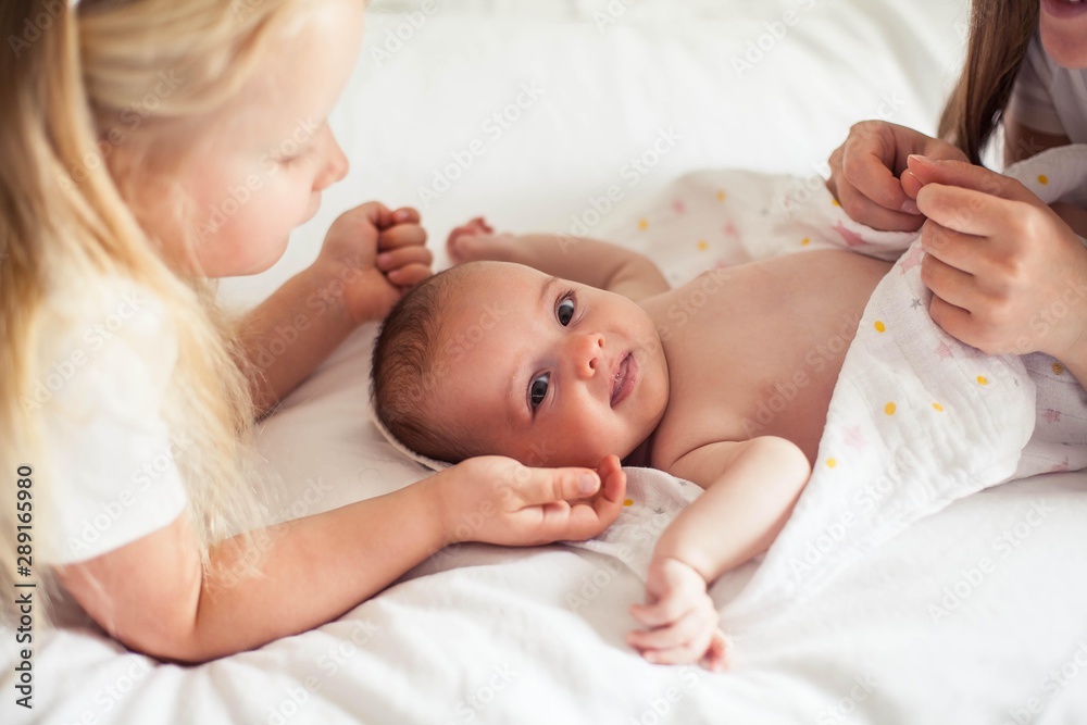 Young beautiful mother holds a baby. Little sister kisses her little sister. Baby. Children bedroom. Young beautiful mother holds a baby. Little sister kisses her little sister. Baby. Children bedroom.