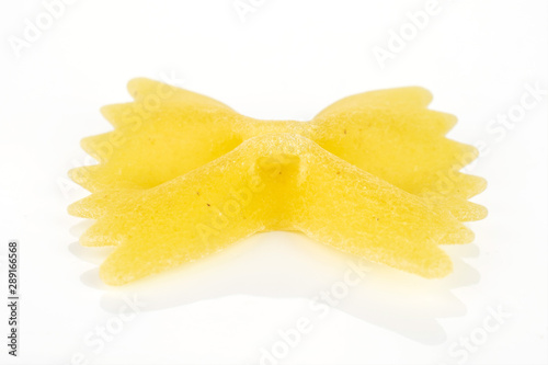 One whole yellow uncooked farfalle isolated on white background