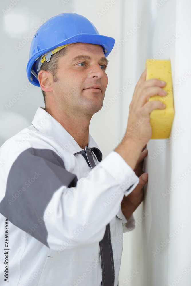 man is cleaning wall with a sponge man is cleaning wall with a sponge