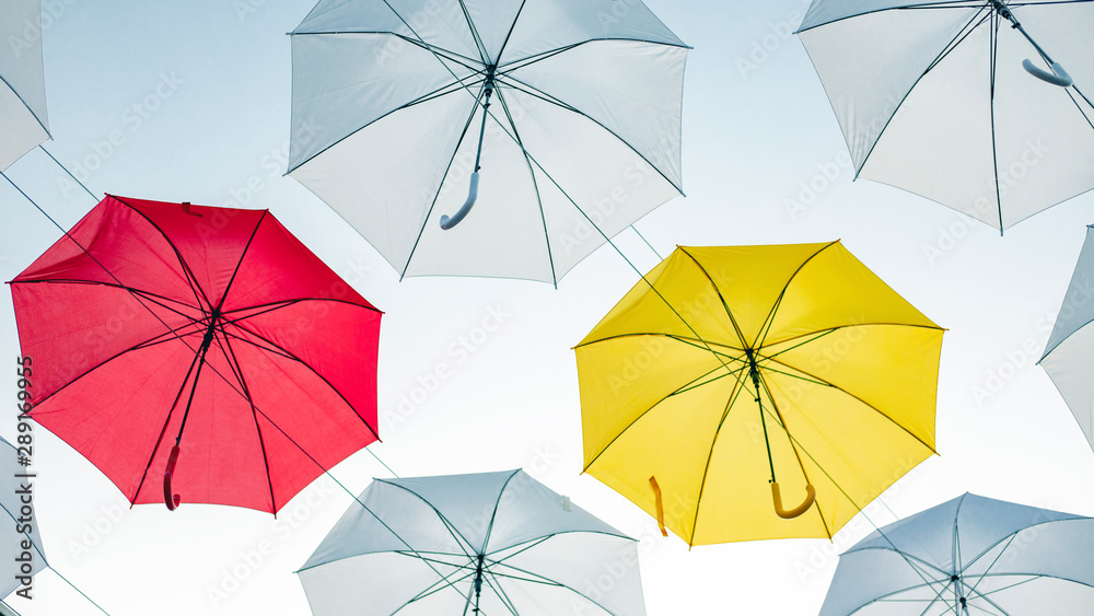 Umbrellas against the blue sky. White, yellow and red umbrella Umbrellas against the blue sky. White, yellow and red umbrella