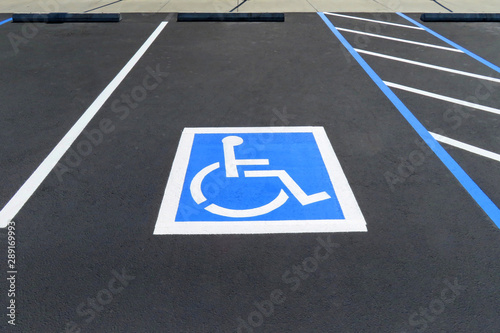 Freshly resurfaced and repainted handicap parking space in a parking lot. The number of handicap spaces increases with the size of the lot, requiring roughly one handicapped spot per 25 spaces.