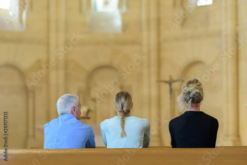 three people sat in church looking towards altar