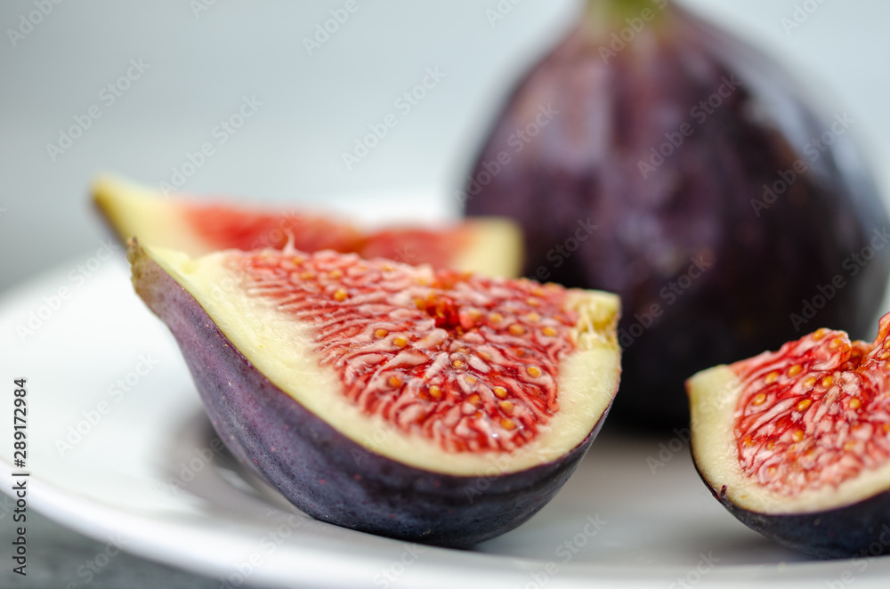 Ripe fig fruits are on the white plate.