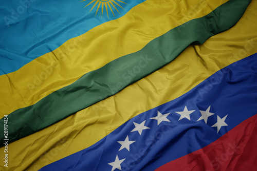 waving colorful flag of venezuela and national flag of rwanda.