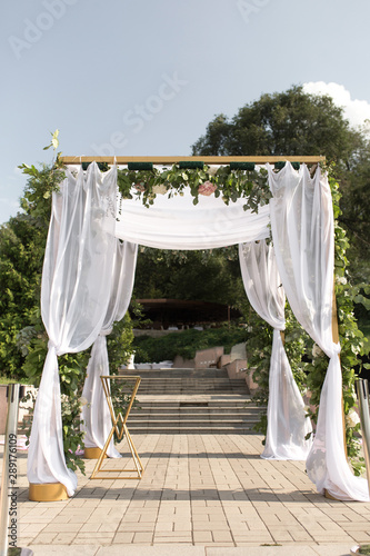 A festive chuppah decorated with fresh beautiful flowers for an outdoor wedding ceremony photo