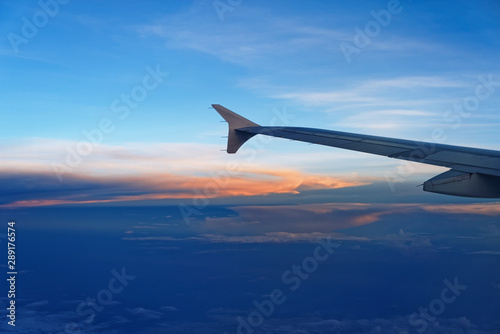 Airplane wing against sky at sunset