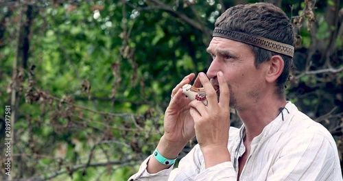 A male musician plays the instruments of the ancient Slavs wind national musical instruments. photo