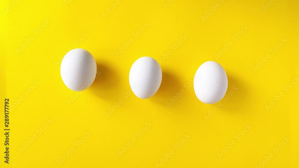 Stop motion animation of three white eggs running on a yellow background and draw an infinity sign. 