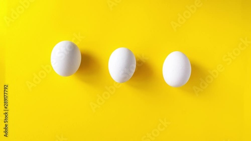Stop motion animation of three white eggs running on a yellow background and draw an infinity sign. 