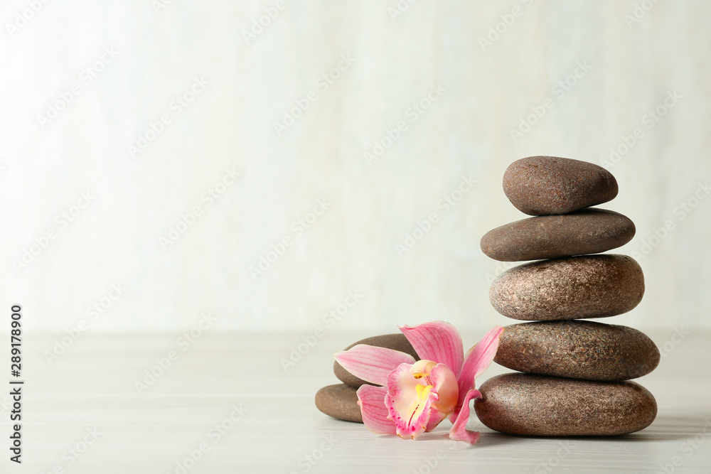 Stack of spa stones and flower on table against white background, space for text - obrazy, fototapety, plakaty 