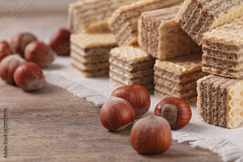 Delicious wafers with hazelnuts on brown wooden background, closeup