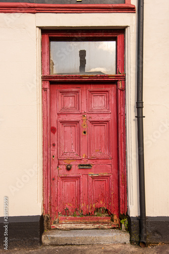 A red door with a transom window along a street in Ireland