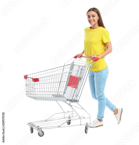 Young woman with empty shopping cart on white background