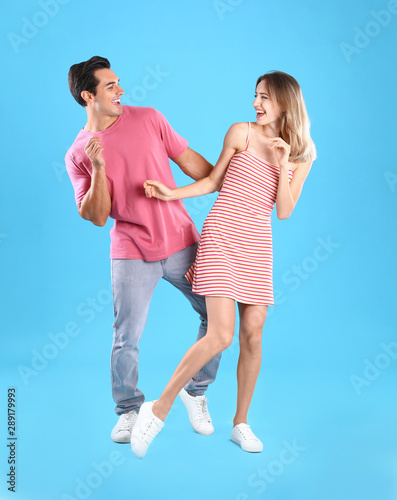 Beautiful young couple dancing on blue background