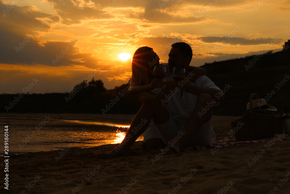 Happy romantic couple drinking wine together on beach Happy romantic couple drinking wine together on beach