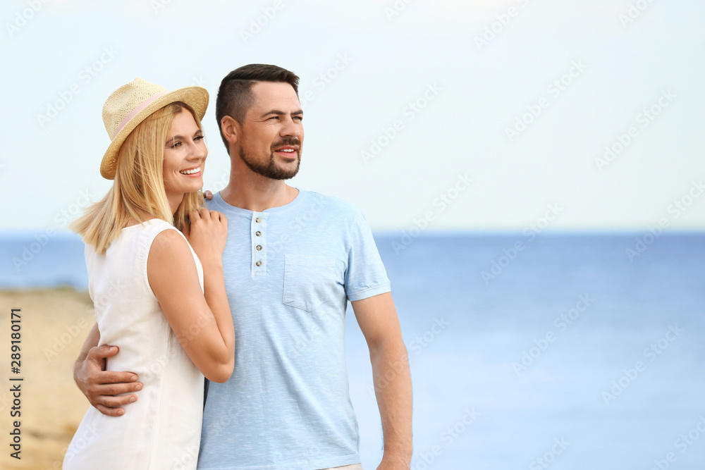 Happy romantic couple spending time together on beach, space for text