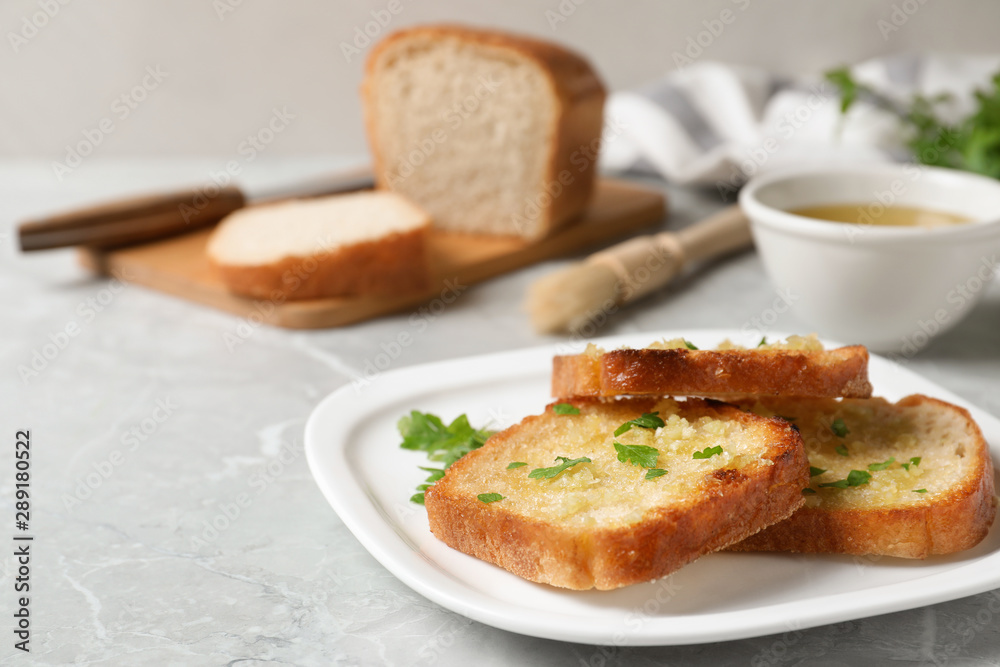 Slices of toasted bread with garlic and herb on light grey marble table Slices of toasted bread with garlic and herb on light grey marble table