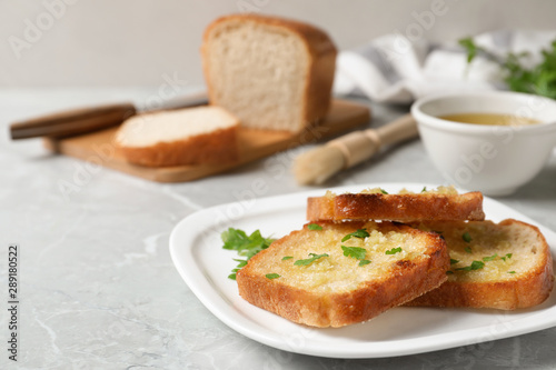 Slices of toasted bread with garlic and herb on light grey marble table