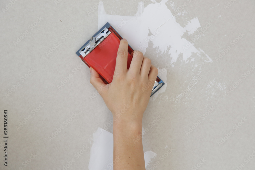 Process of sanding wall with a sanding block after skim coating
