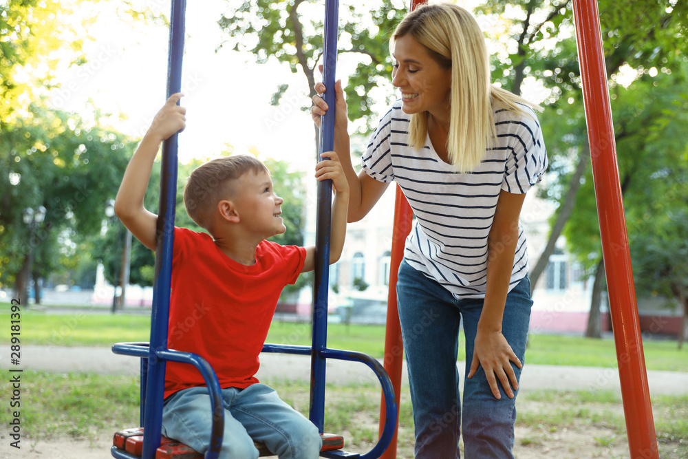 Nanny and cute little boy on swing in park Nanny and cute little boy on swing in park