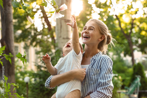 Teen nanny with cute baby in park on sunny day