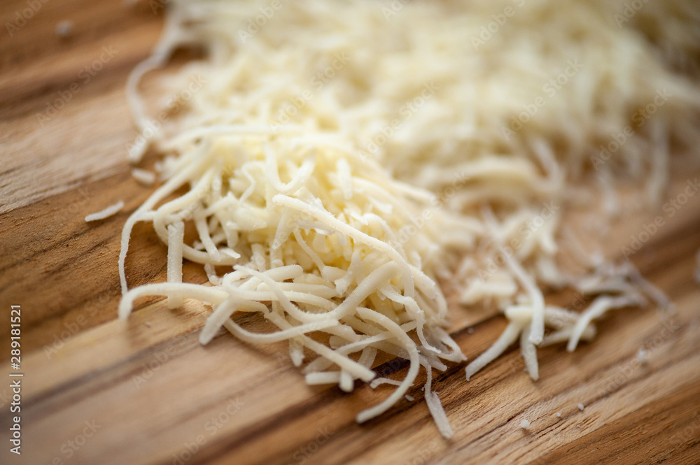 Shredded white cheese on rustic wooden cutting board