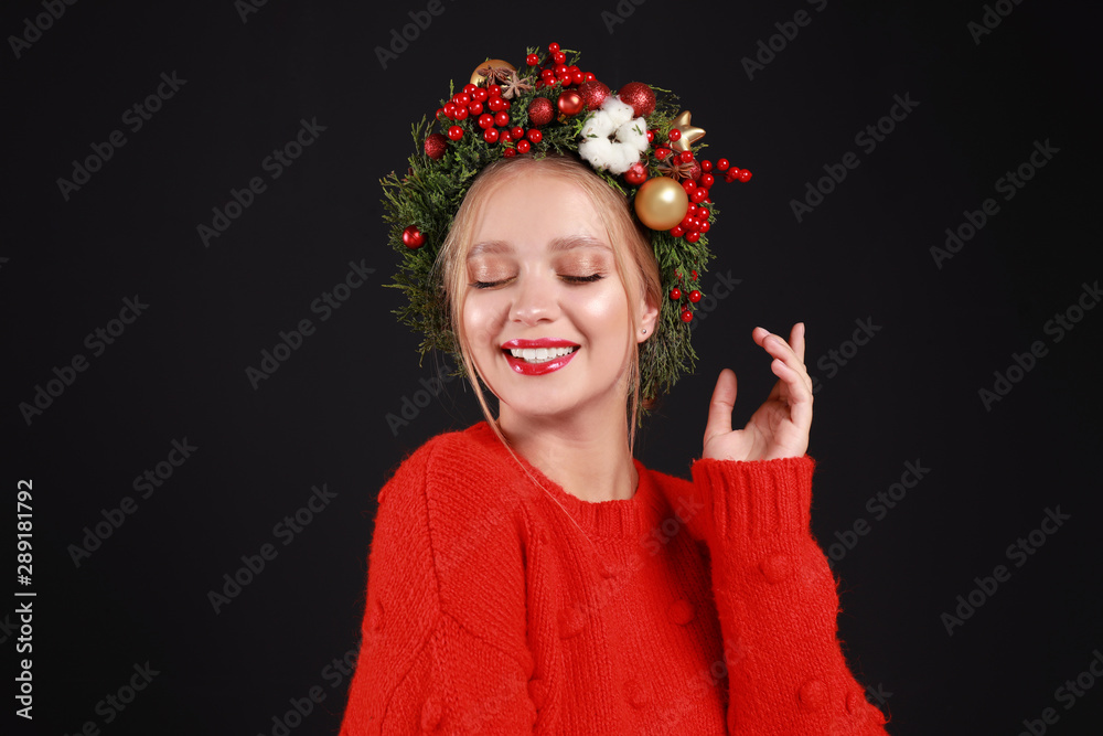 Beautiful young woman wearing Christmas wreath on black background Beautiful young woman wearing Christmas wreath on black background