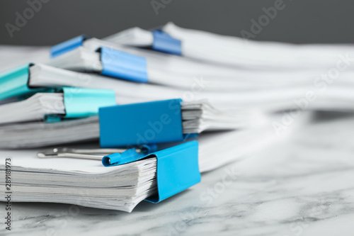 Stack of documents with binder clips on marble table, closeup photo