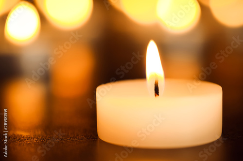 Burning candle on table, closeup. Funeral symbol