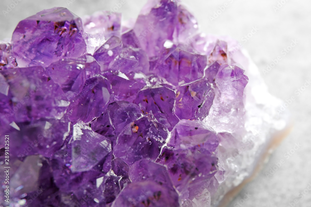 Fototapeta premium Beautiful purple amethyst gemstone on grey table, closeup