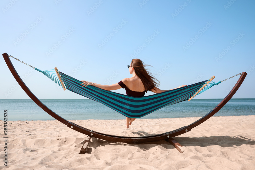 Fototapeta premium Young woman relaxing in hammock on beach