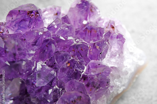 Beautiful purple amethyst gemstone on grey table, closeup
