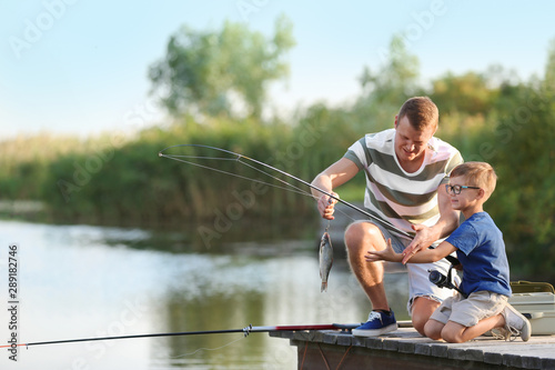 Dad and son fishing together on sunny day