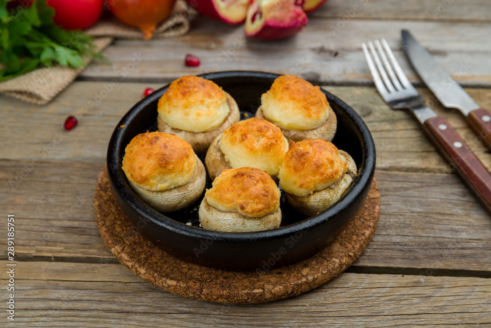 mushrooms baked with Suluguni cheese on old wooden table mushrooms baked with Suluguni cheese on old wooden table