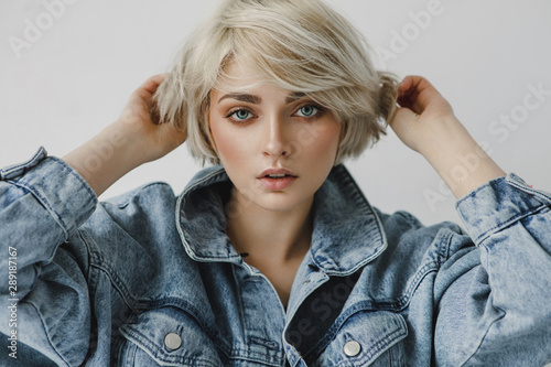 Portrait of fashion blonde woman touching short hair wear denim jacket